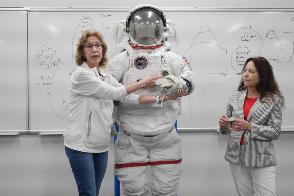 Cinda Chullen (left) demonstrates one of the space suits astronauts use for EVAs outside the ISS.