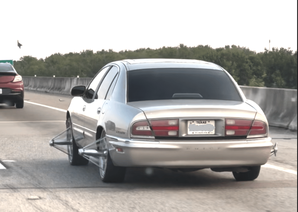 A gray car with god damn 40 cm spikes sticking out from its hub caps.