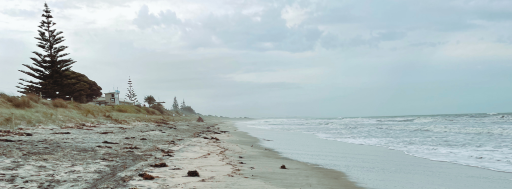 A bleak looking white sand New Zealand beach.