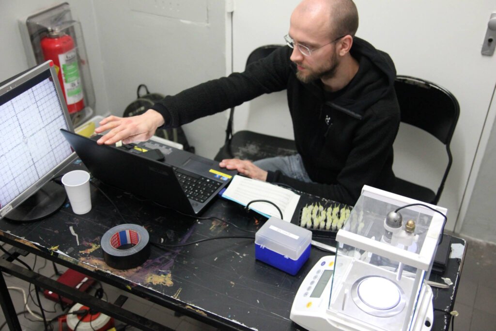 A man sits at a desk while checking peoples' drugs.
